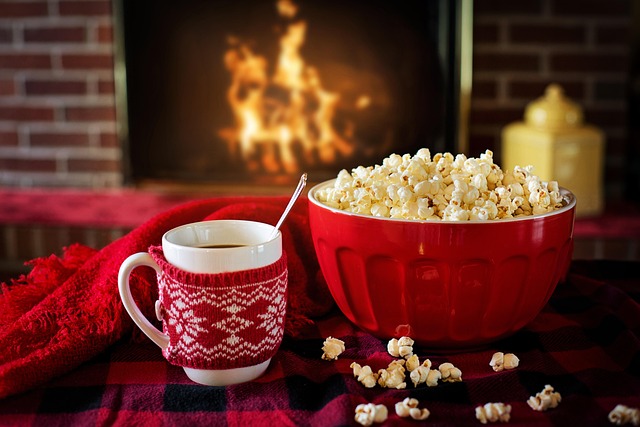 bowl of popcorn and mug with fireplace fire in background