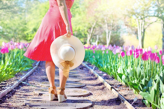 woman in a dress with a hat in her hand and tulips in the background